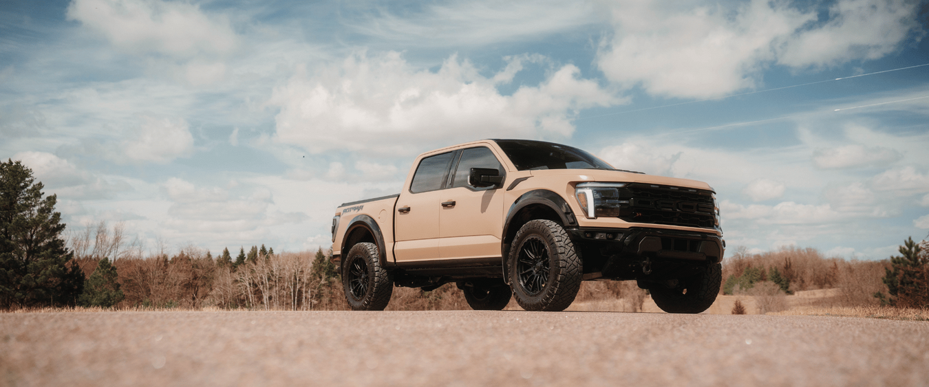 Beige pickup truck on a dirt road with a clear sky