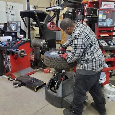 Person working on a tire using a tire changer in a garage setting.